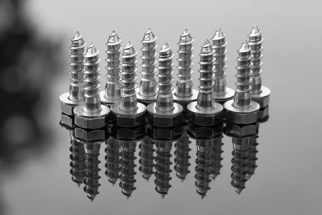 A close-up image of shiny silver hex bolts arranged neatly in rows on a white background.